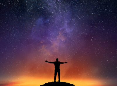 Businessman exults on a mountain with starry sky background